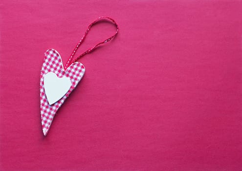 A fabric heart in pink on a paper background