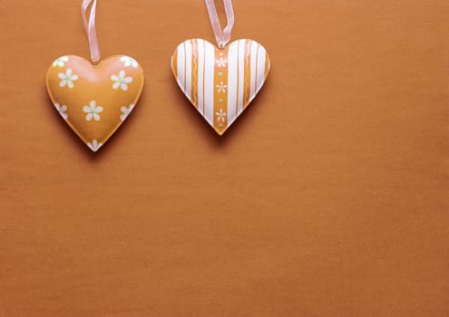 Two metal hearts in Peach Fuzz on a paper background