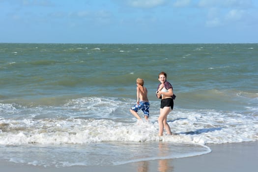 A boy and a teenage girl have fun in the waves on the sea beach
