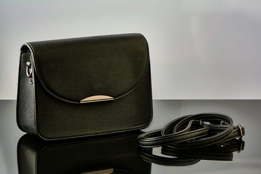 A black handbag stands on black glass. High quality photo