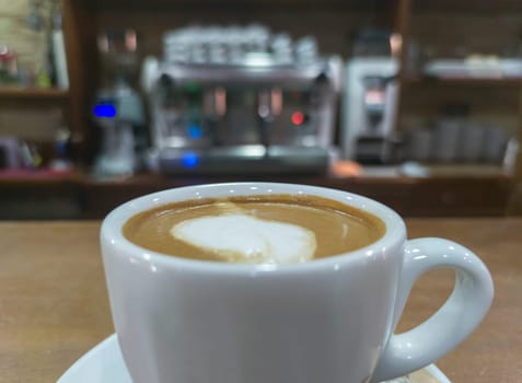 Coffee cup served over bar counter. Profesional expresso coffee machine at background