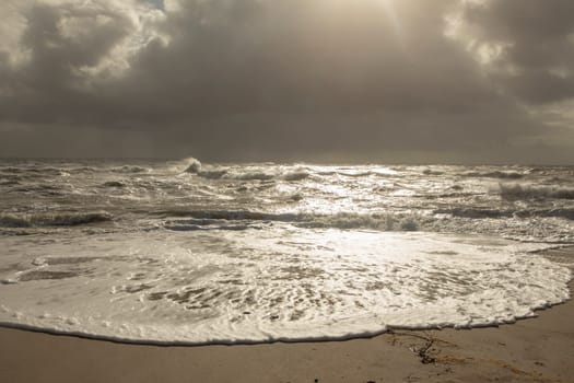 sea landscape with huge waves and a lightbeam in Sylt, Germany