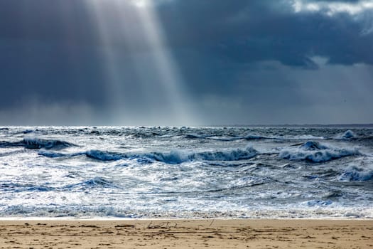 sea landscape with huge waves and a lightbeam in Sylt, Germany