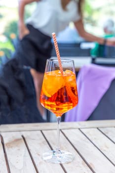 summer aperitif drink with alcohol and ice and straw on outdoor table