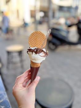 ice cream in a cone with chocolate holding by a young hand