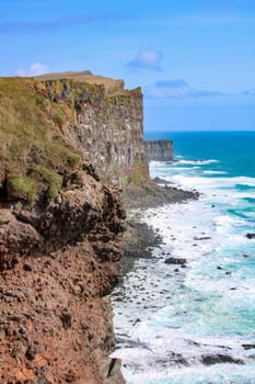 Picturesque view of western fjords in Iceland. Cliffs and mountains with green grass. Steep cliffs and crashing waves of Atlantic Ocean below. Coastline and ocean icelandic shore. Latrabjarg
