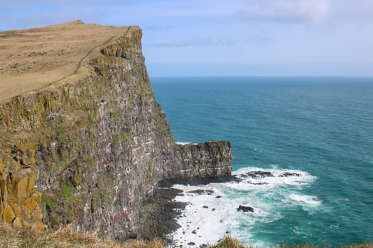 Picturesque view of western fjords in Iceland. Cliffs and mountains with green grass. Steep cliffs and crashing waves of Atlantic Ocean below. Coastline and ocean icelandic shore. Latrabjarg