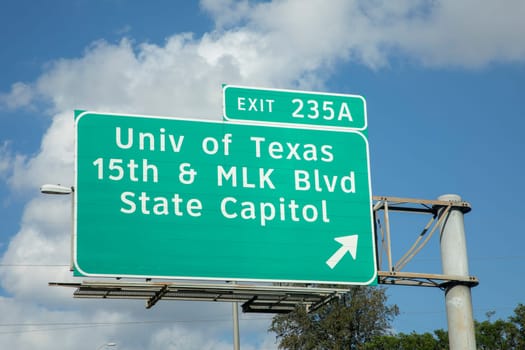 exit University of Texas and State Capitol in Austin from  interstate 35 in afternoon sun with clouds