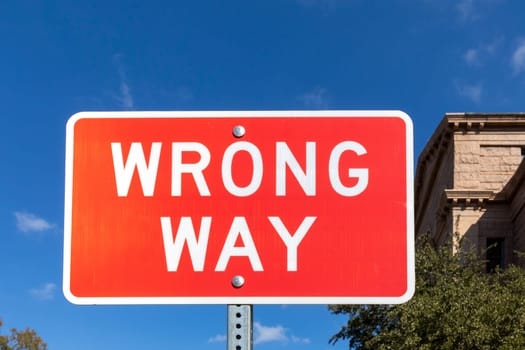 warning sign wrong way on red background under blue sky