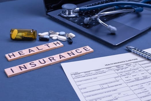 Health insurance form claim with laptop, stethoscope and pills on table. Medical insurance, health risk, pay for the healthcare concept.