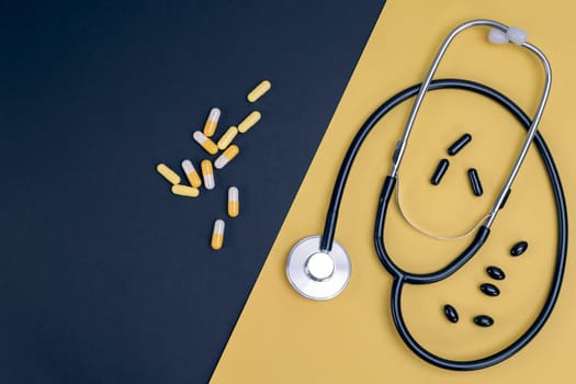 Stethoscope and capsules on yellow and black background. Healthcare, medical exam, insurance,  concept.