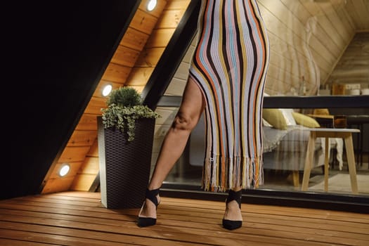 Cropped image of female legs in stilettos and knit beach dress