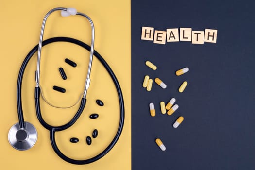 Stethoscope and capsules on yellow and black background. Healthcare, medical exam, insurance,  concept.