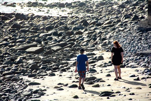 Young woman with a short black dress and a boy on a stony beach,Young woman with a short black dress and a boy on a stony beach