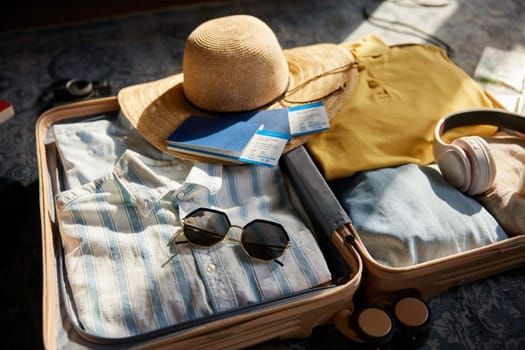 Suitcase packed with clothes, hat and personal belongings for travel. Male and female luggage bag with vacation stuff kit