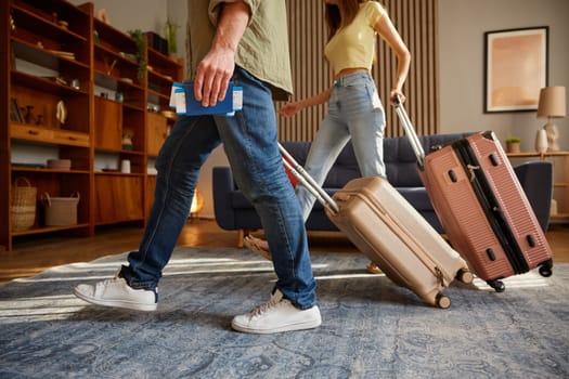 Closeup man and woman walking with luggage and travel documents leaving home. Family couple travelling together