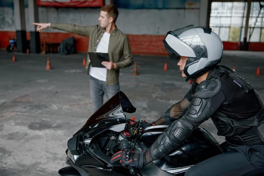 Driving practice at motorcycle driver training center with indoor motordrome. Learning to ride motorbike