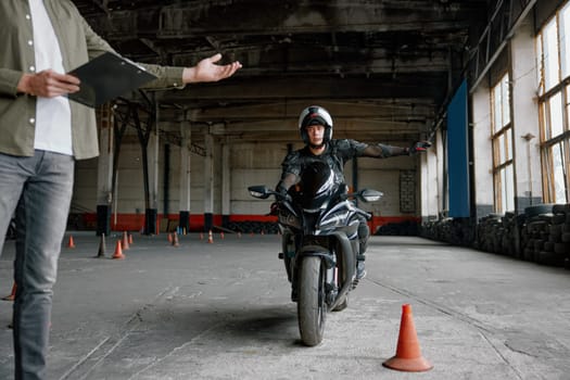 Male student learning how to drive motorcycle with one hand. Lesson with instructor at motorbike driving school