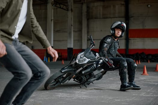 Instructor explaining student motorcyclist his mistake at training class. Driving course and professional education for safety motocross riding