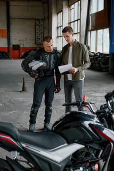 Student motorcyclist and instructor looking at test exam list checking mistake or understanding nuances of driving at high speed