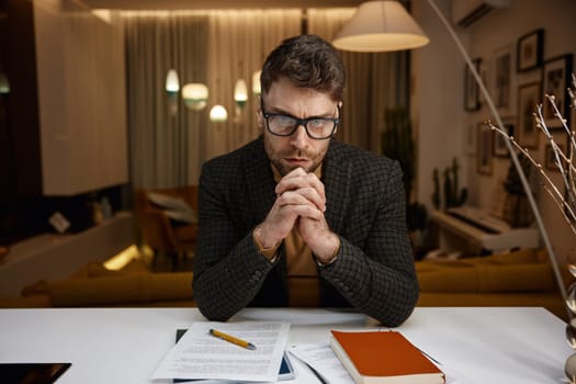 Portrait of serious focused businessman looking at camera webcam view. Handsome young intelligent male worker in business suit listening to conversation during online virtual conference