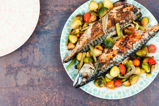 Plate with whole baked mackerel fish and tomatoes, cabbage and green beans