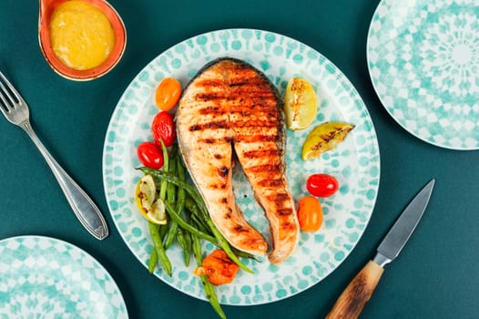 Grilled salmon steak with grilled potatoes and green beans. Fried fish.