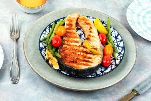 Grilled salmon steak with grilled potatoes and green beans. Fried fish.