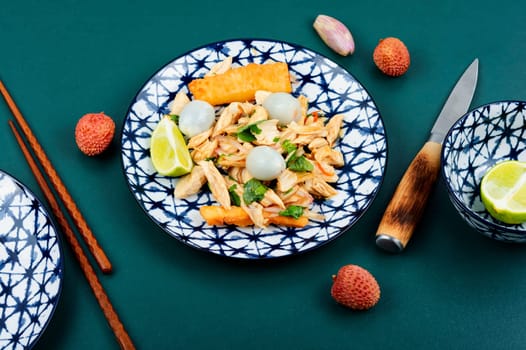 Plate of spicy Asian salad with lychee or litchi and chicken breast. Asian food. Top view.