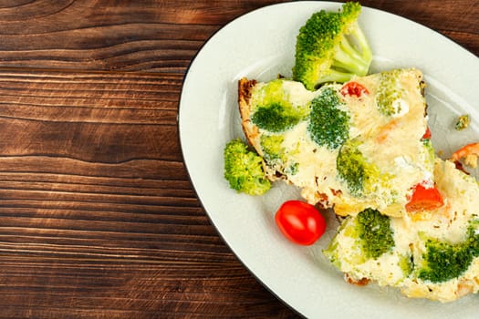 Omelette with broccoli, shrimp and cherry tomato on a rustic wooden texture. Space for text.