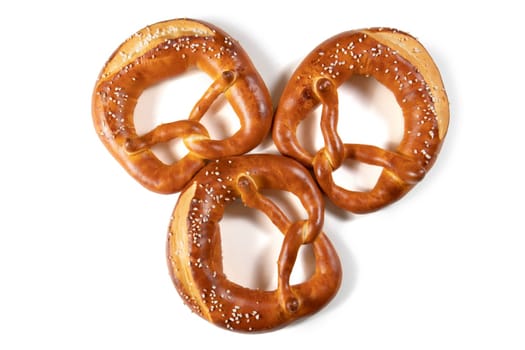 Three  Bavarian pretzel top view with salt on a white background. The pretzel is shaped like a knot, and it is covered in a generous amount of salt. The pretzel is golden brown in color, and it looks crunchy and delicious.