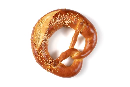 Golden brown Bavarian pretzel with a generous amount of sesame seeds sprinkled over it, from above on a white background. The pretzel's knotted shape and crispy texture are enticing and visual appeal