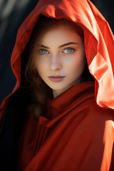 A captivating woman with mesmerizing blue eyes confidently poses while draped in a bold red cloak.