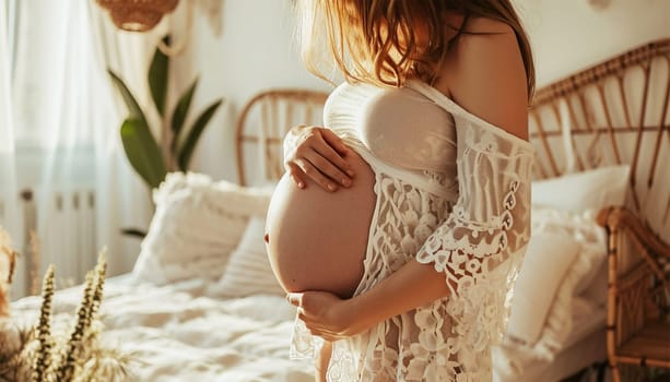 Beautiful pregnant woman holds hands on belly in bedroom at home. Young mother waiting of a baby. Concept of pregnancy, maternity, health care, gynecology, medicine. Close-up, indoors. Stylish boho interior beauty