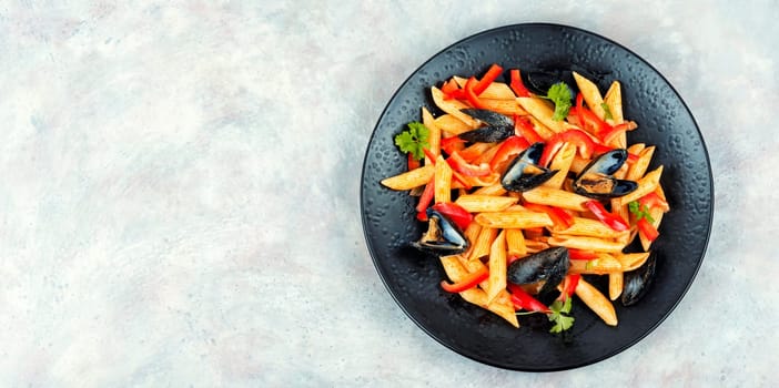 Macaroni with Atlantic mussels on a dark plate. Pasta with seafood. Noodles with mussels on wooden table. Top view.
