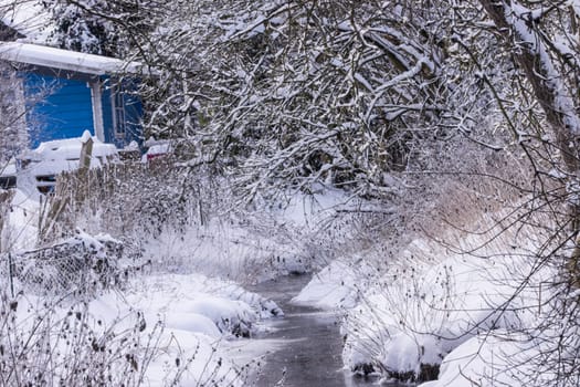 Winterlandschaft mit Bach und blauem Gartenhaus, Nordrhein-Westfalen, Deutschland