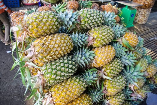 A pile of folded pineapple on the market. Sweet ripe pineapple. A pile of folded pineapple on the market. Sweet ripe pineapple.