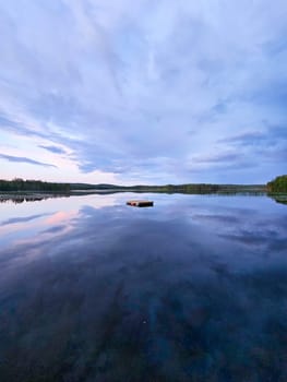 Swimming island in Sweden on a lake at sunset. Clouds reflected in the water. Swimming fun on vacation with recreation in Scandinavia