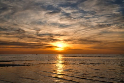 Sunset, illuminated sea. Sandy beach in the foreground. Light waves. Poel island on the Baltic Sea. Nature photo from the coast