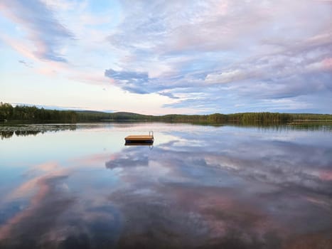 Swimming island in Sweden on a lake at sunset. Clouds reflected in the water. Swimming fun on vacation with recreation in Scandinavia