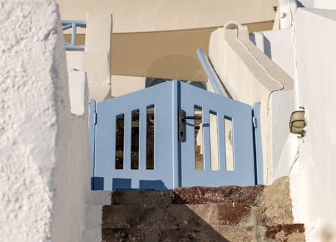 Closed blue wicket and narrow stone steps, a traditional piece of architecture on the island of Santorini. Greece