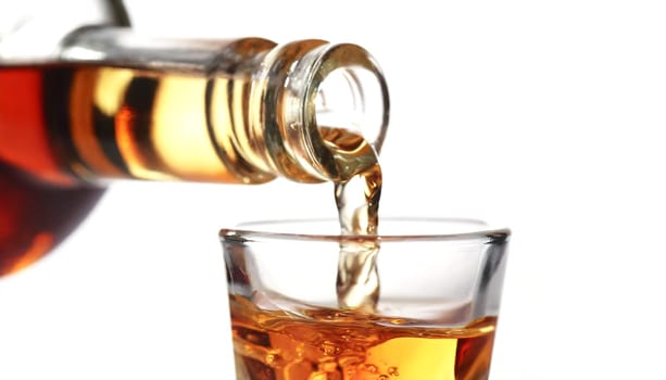 Whiskey being poured into a glass from a bottle on a white background. AI generated