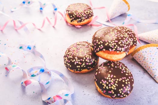 Carnival food. German Krapfen or donuts with streamers and confetti. Traditional Berliner for carnival and party.