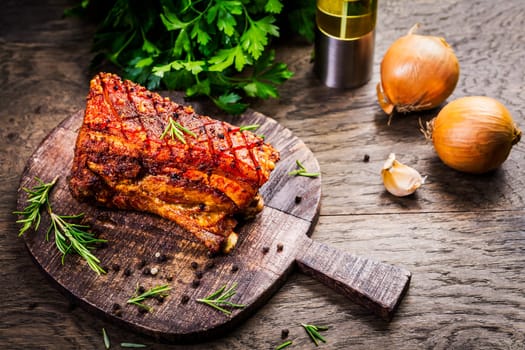 Grilled pork belly with crispy skin, with onion and herbs  on wooden background