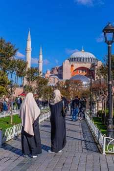 Istanbul, Turkey - November 14, 2023. Women at the Sultan Ahmet Park in front of Hagia Sophia Grand Mosque and Hagia Sophia Hurrem Sultan Bathhouse. Sultanahmet neighbourhood, City of Istanbul, Turkey.