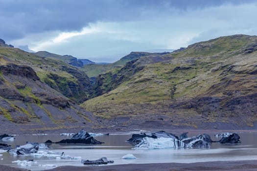 Solheimajokull picturesque glacier in southern Iceland. The tongue of this glacier slides from the volcano Katla. Beautiful glacial lake lagoon with blocks of ice