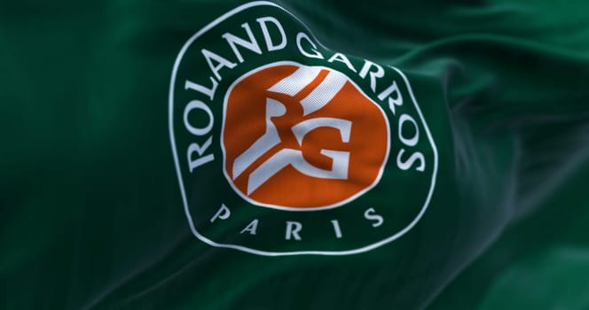 Paris, FR, Apr. 2023: Green flag with Roland Garros logo waving in the wind. French Open is a major tennis tournament scheduled in late May each year. Illustrative editorial 3d illustration render