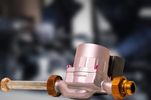 Electric circulation pump of a condensing gas heating system over blurred industrial background. Used spare parts for condensing gas heaters. Gas boiler repair. Macro.