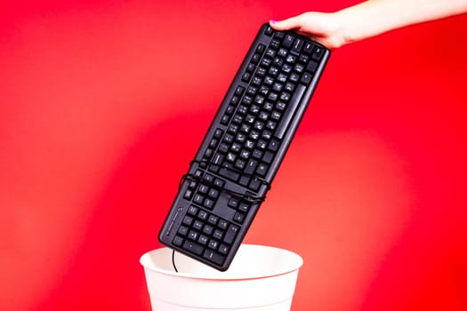 Woman putting a computer keyboard in a e-waste trash bin, recycling concept