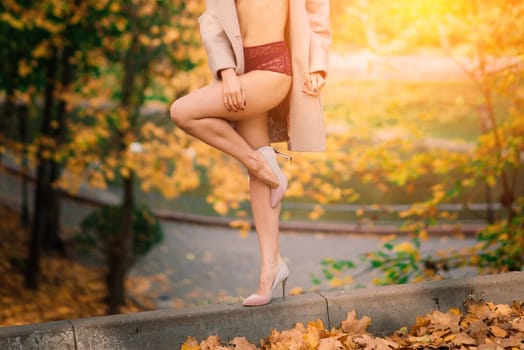 Fashion image of perfect long slim woman legs in an autumn park.